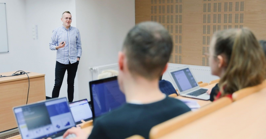 fot.fot. Andrzej Romański Wykładowca prowadzi zajęcia ze studentami, studenci siedzą tyłem do fotografa i mają włączone komputery