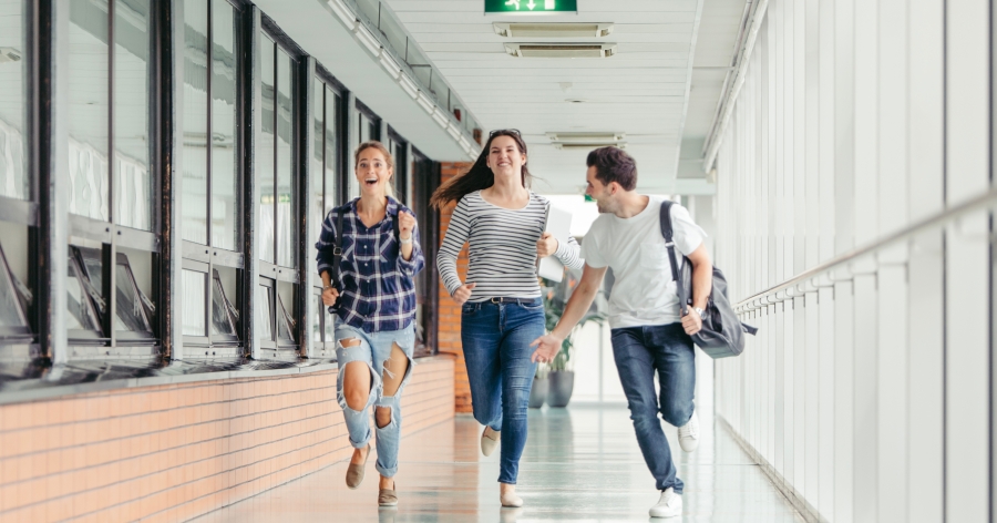 Biegnący przez korytarz student i studentka