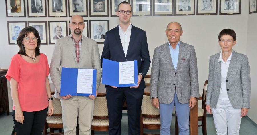 Dr inż. Krystian Erwiński oraz dr inż. Rafał Szczepański zostali ambasadorami otwartej nauki w ramach pilotażowego programu Full Open Science fot.fot. Andrzej Romański Zdjęcie pozowane, pięć osób stoi w gabinecie przed stołem, laureaci trzymają otwarte teczki z certyfikatem
