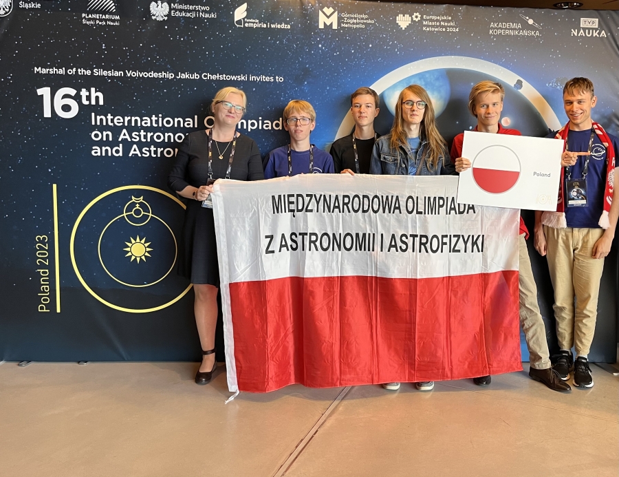 Laureaci Olimpiady fot.nadesłane Stojący laureaci Olimpiady wraz z opiekunem dr Karolina Bąkowską. Wszyscy trzymają polską flagę.