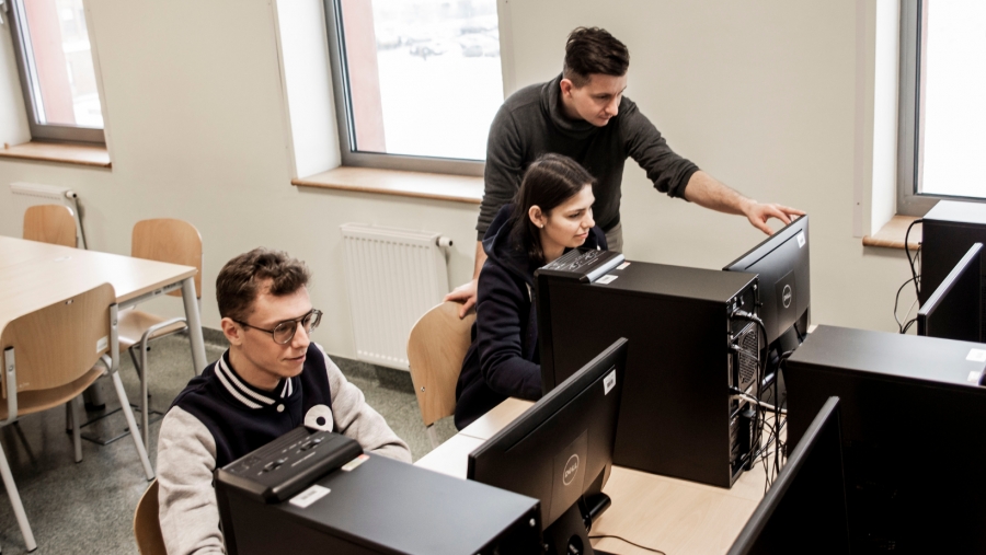 obrazek: fot.Sonia Tlili Dwójka studentów siedzi przed monitorami, wykładowca stoi i coś im pokazuje