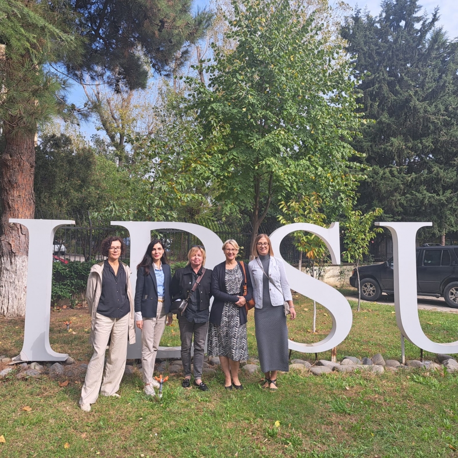 The photo shows a group of lecturers (5 women) against the background of an installation of human-sized letters forming the abbreviation of the name of the International University of the Black Sea. The installation is part of a park belonging to the university.