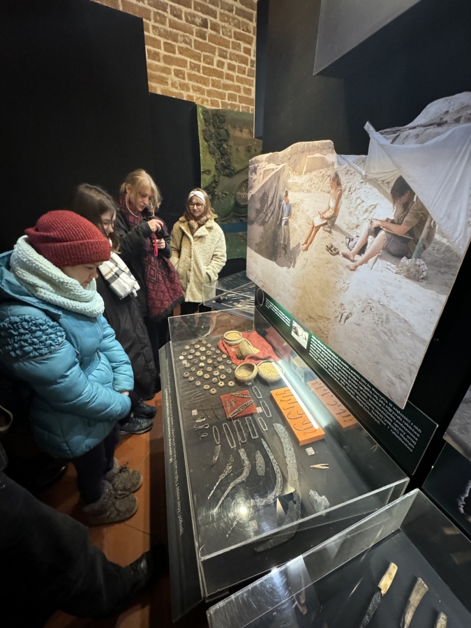 Grupa studentów stojąca przed gablotą z artefaktami archeologicznymi w muzemu