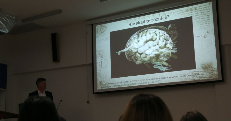 ekran na którym wyświetlany jest obraz mózgu. Po lewej stoi i patrzy się na ekran prelegent