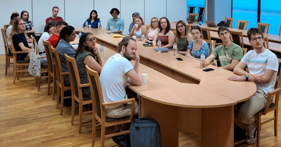 Oprócz pracy nad projektami, stażyści mieli okazję zapoznać się z badaniami prowadzonymi na Wydziale Fizyki, Astronomii i Informatyki Stosowanej oraz na Wydziale Matematyki i Informatyki fot.Kamil Fedus/Robert Skiba Grupa studentów, uczestników programu letniego, siedzi przy owalnym stole i słuchają wykładu, ich głowy skierowane są w stronę prelegentów, których nie widać na zdjęciu