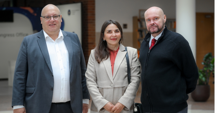 dr hab. Maciej Krotofil, prof. UMK, dr Rusłana Marceniuk, dr Ołeksij Sokyrko fot.Andrzej Romański Dwóch mężczyzn i kobiieta w oficjalnych strojach w holu Collegium Humanisticum UMK