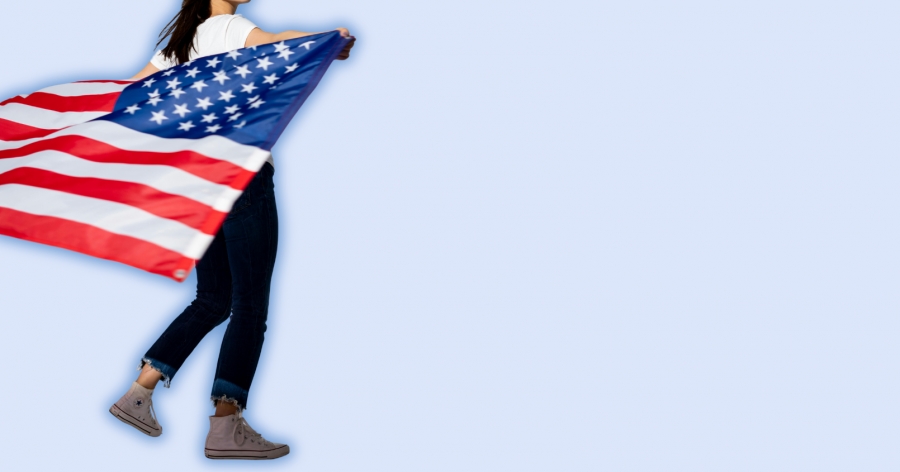 Dziewczyna trzyma na plecach flagę USA.