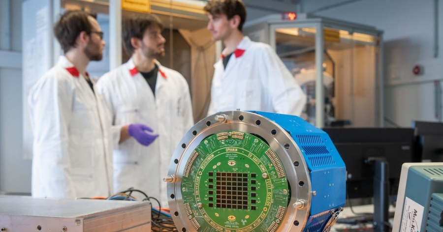 Nad badaniami i eksperymentami pracowała międzynarodowa grupa naukowców w CERN, w tym fizycy z Uniwersytetu Mikołaja Kopernika w Toruniu fot.fot. AEgIS/CERN Na pierwszym planie urządzenie w postaci niebieskiego walca z zielonymi elementami, w tle trzech naukowców w białych fartuchach
