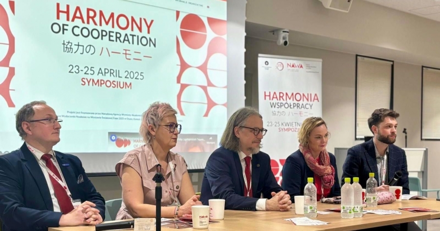 W dniach 23-25 kwietnia 2025 r. na naszym partnerskim Uniwersytecie Kobe odbyło się sympozjum naukowe "Harmonia Współpracy" fot.Bartosz Zdunowski Pięcioro prelegentów siedzi przy stole konferencyjnym, w tle ekran z prezentacją. Widać na nim tytuł sympozjum Harmonia współpracy po angielsku i po japońsku