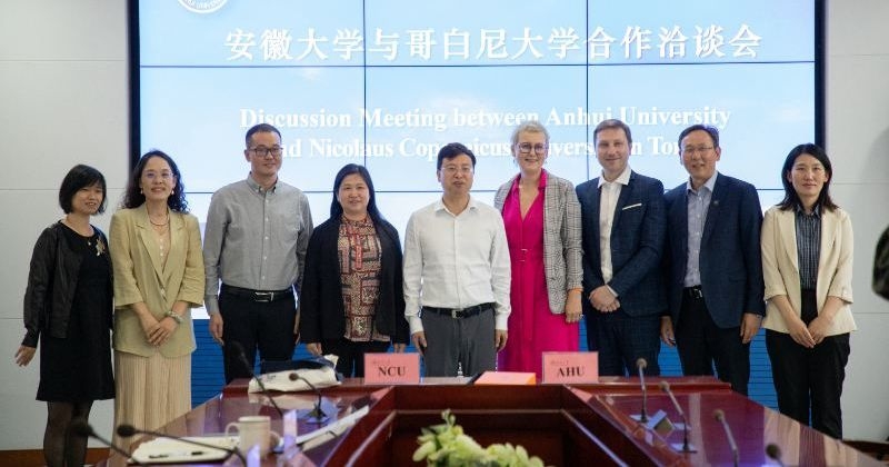 Dzięki porozumieniu z Anhui University osoby uczące się języka chińskiego na UMK będą mogły bezpłatnie studiować na uczelni partnerskiej, otrzymają również darmowe zakwaterowanie. fot.Nadesłane Dziewięć osób z polskiej i chińskiej uczelni stoi na tle prezentacji