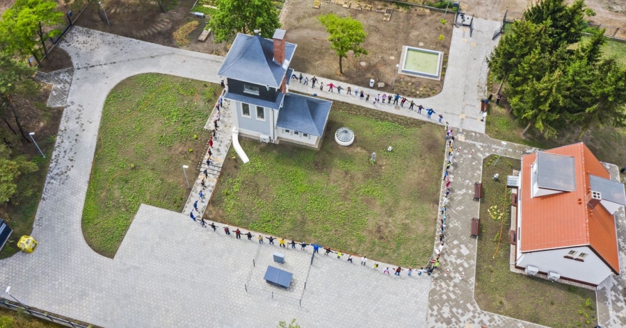 The programme will include language classes, art and ecology workshops, and shared care of the community garden photo:fot. Andrzej Romański An aerial view of the Copernican Integration Centre building. People are standing around the building, holding hands.
