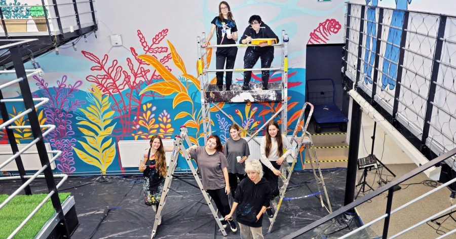 The painting arrangement of the 'Kotłownia' Centre space was carried out by students of painting at the Wall Painting Studio of the NCU Faculty of Fine Arts photo:Andrzej Romański Seven people involved in painting the mural in front of their work, scaffolding and ladders still visible.