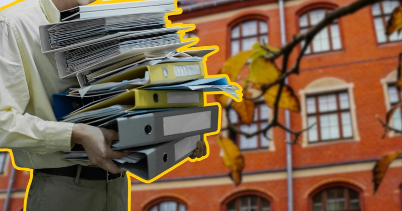 Na pierwszym planie osoba trzyma stos dokumnetów. W tle budynek Collegium Maius.