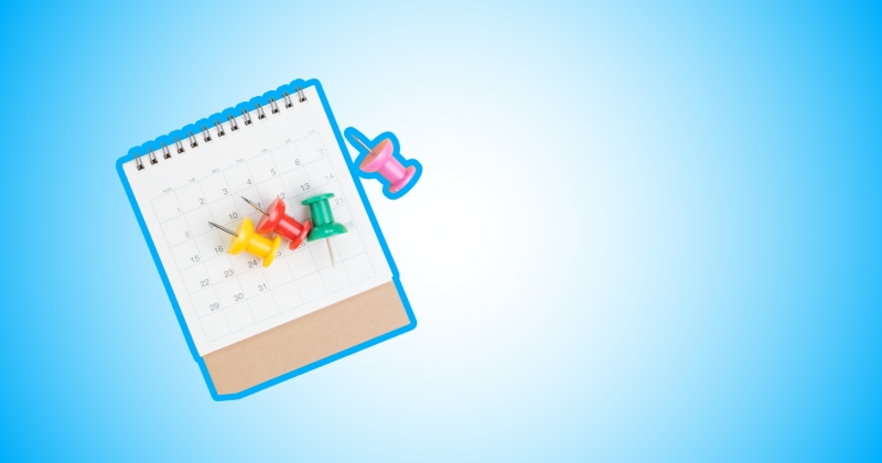 Na jasnoniebieskim tle kalendarz. Na nim 4 pinezki.
