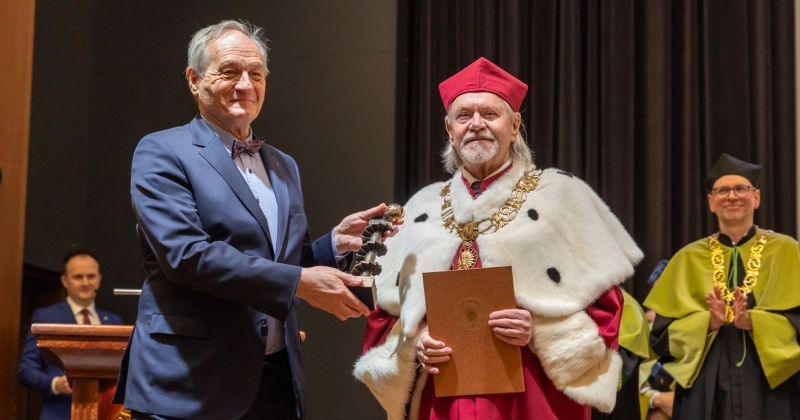 Kolegium rektorskie w uroczystych strojach (gronostaje) za stołem prezydialnym. w tle ekran z logo UMK i napsiem Święto Uniwersytetu 2026