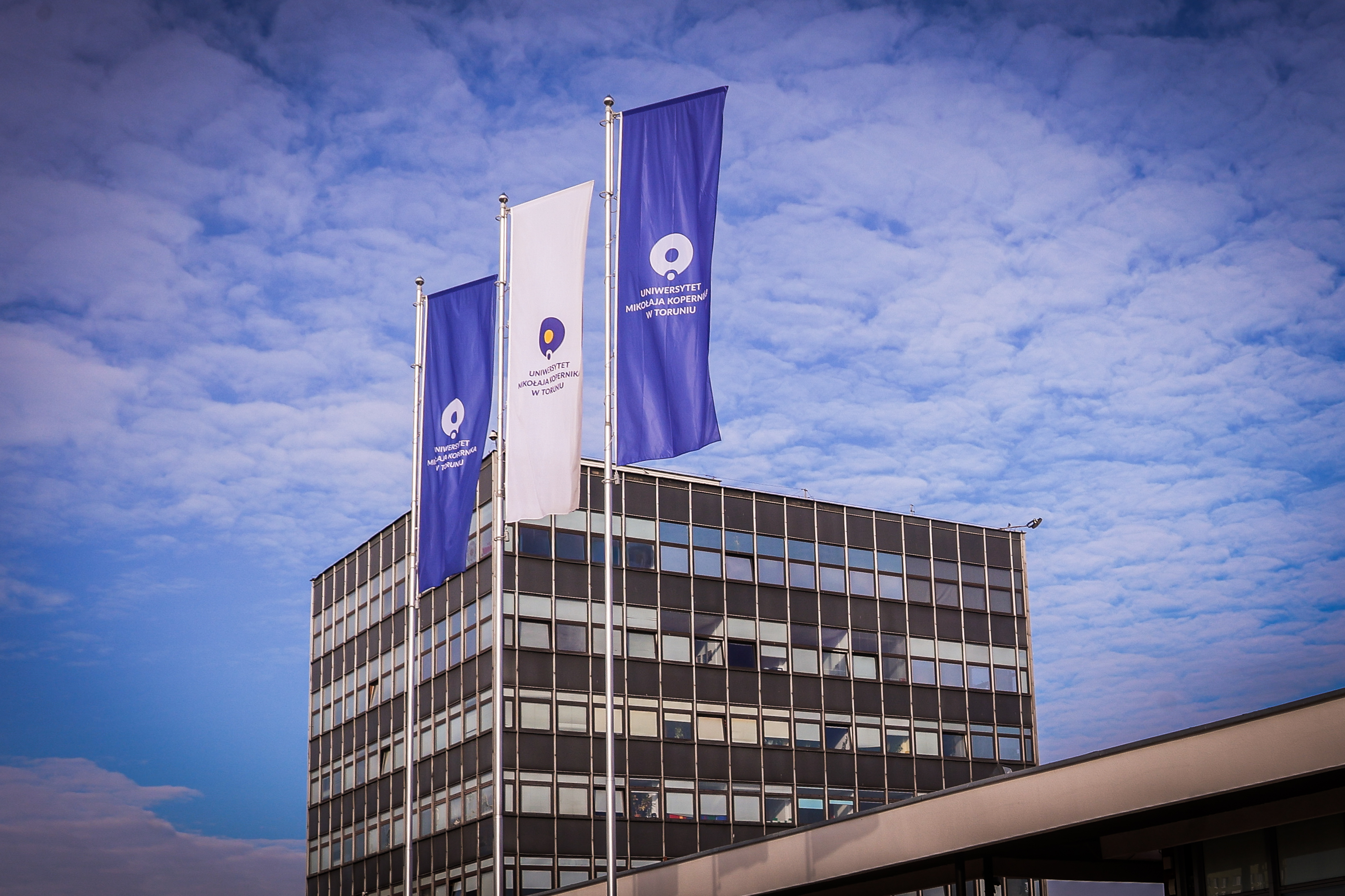 Widok na rektorat UMK< przed nim flagi uniwersyteckie