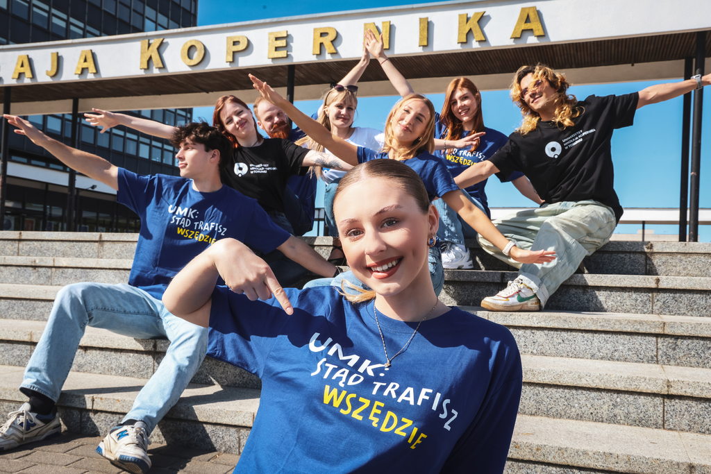 Studenci siedzący na schodach przed rektorat, ubrani w koszulki z logo UMK.