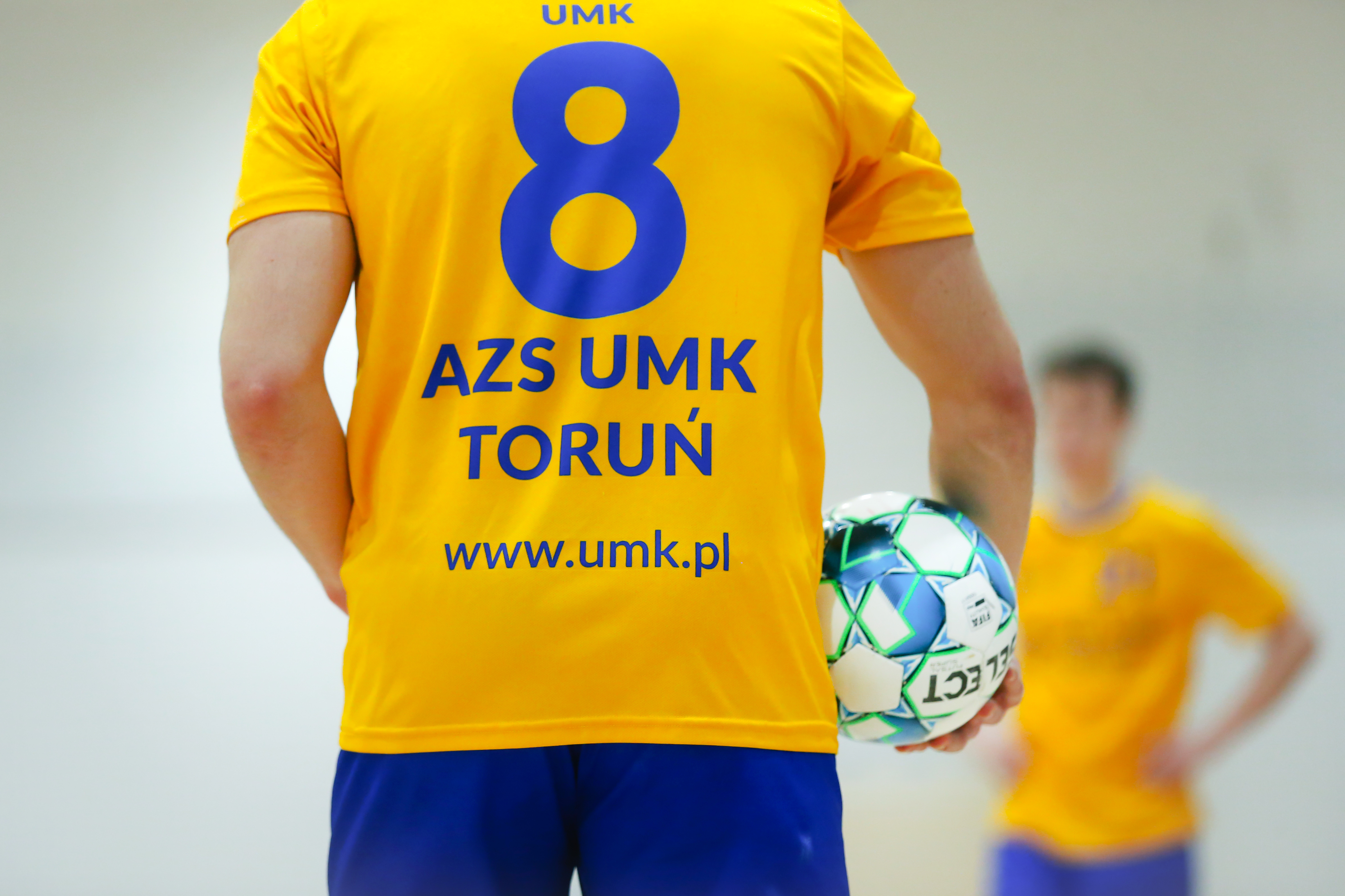 Zdjęcie przedstawia sportowca w koszulce AZS UMK, widzianego z tyłu.