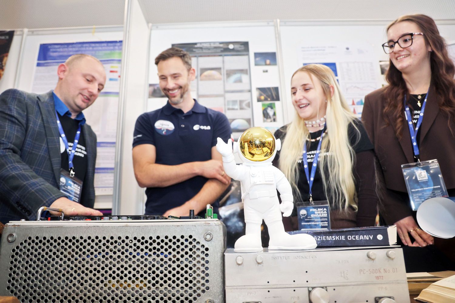 figurka astronauty, w tle cztery osoby, w tym Sławosz Uznański-WIśniewski