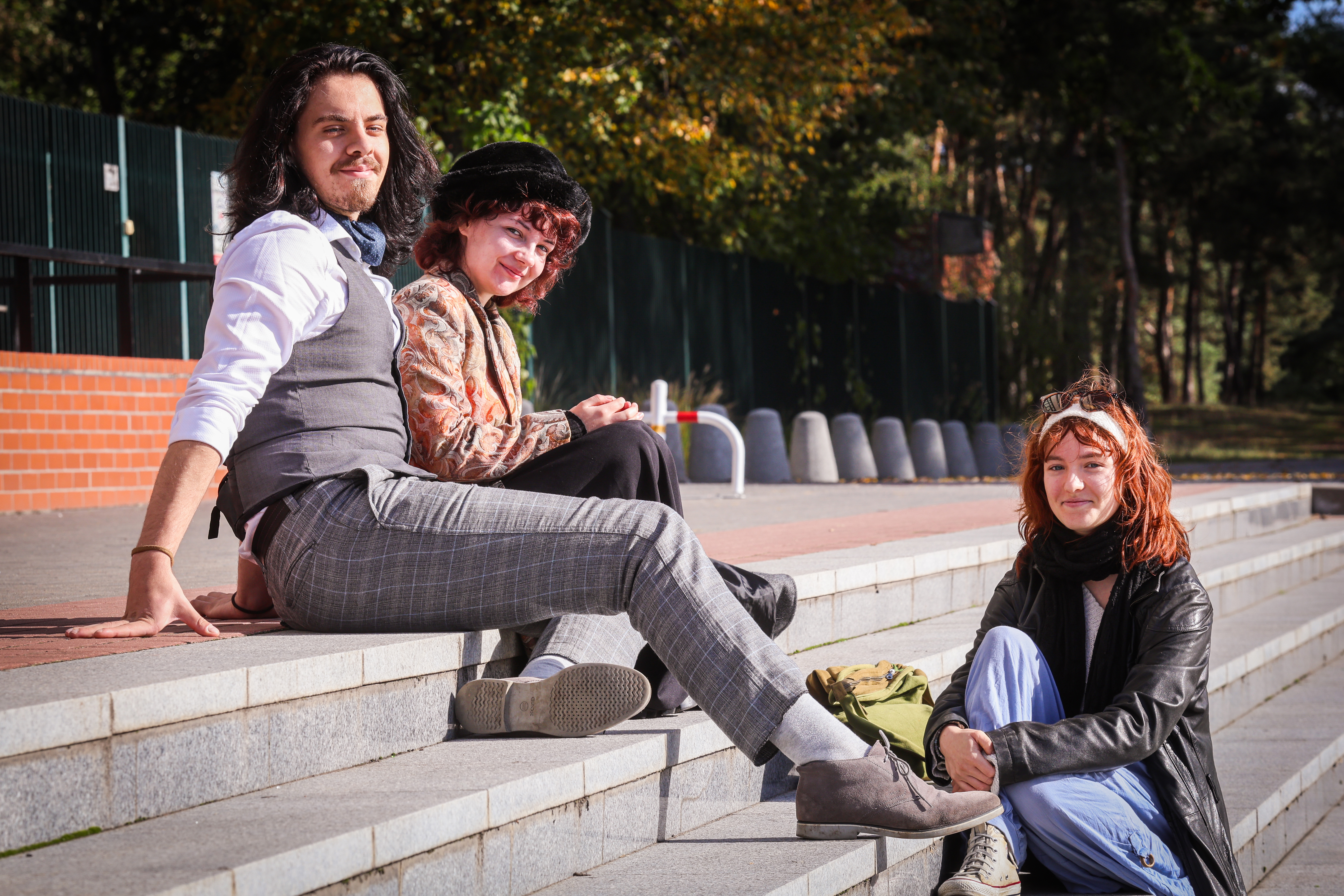 Three students are sitting by the pool on campus