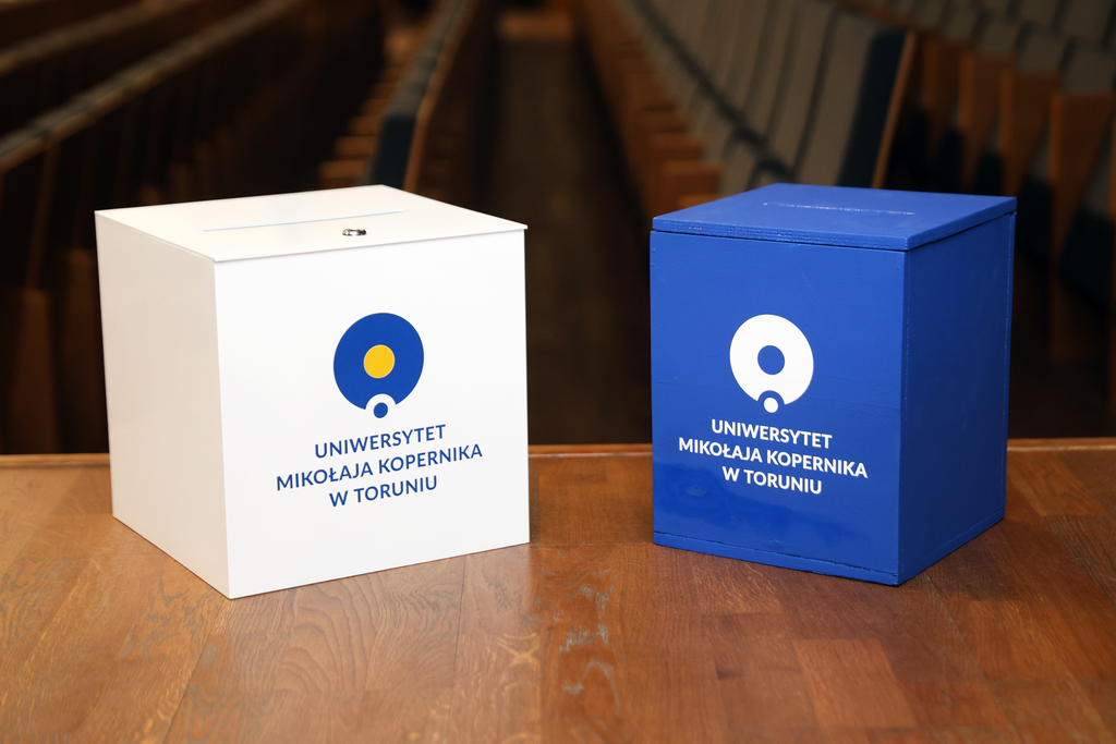 Zdjęcie przedstawia dwie urny wyborcze z logo UMK.