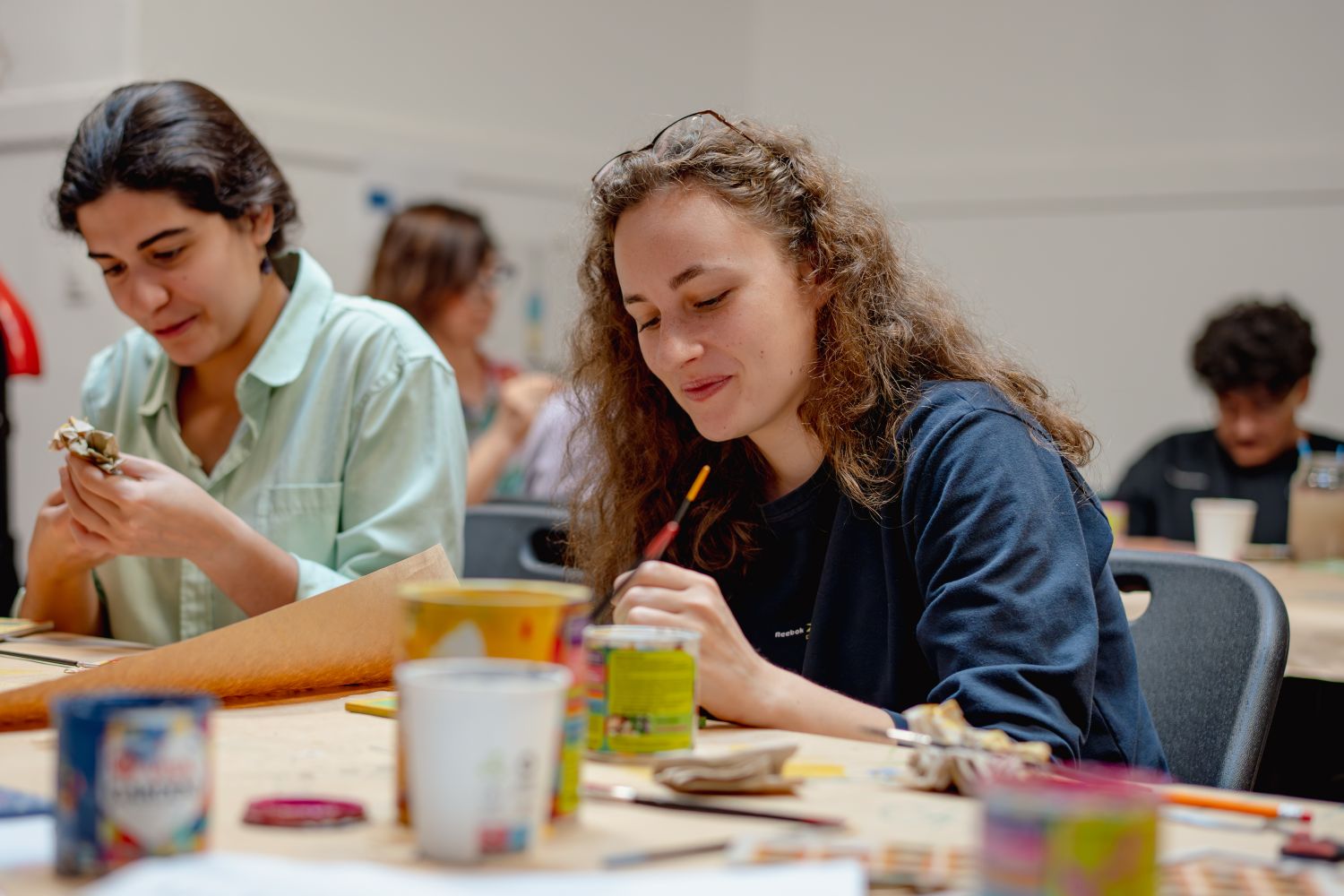 young people sit at the table doing arts and crafts