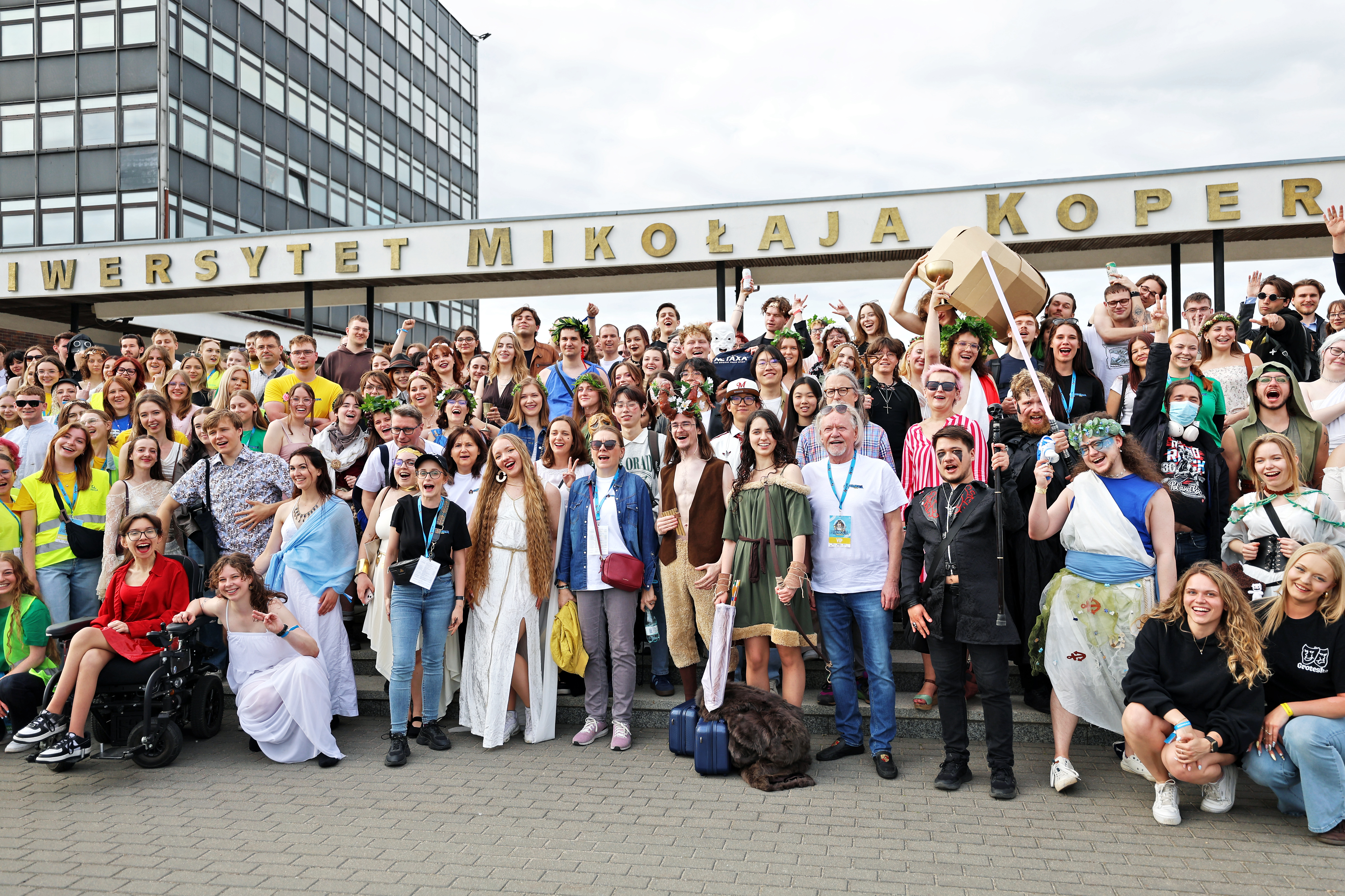 a group of students in colorful clothes poses in front of the NCU rectorate during the Juwenalia
