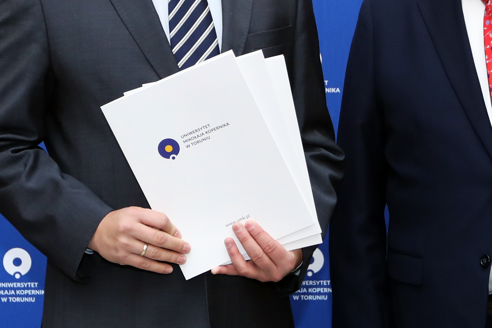 a man in a suit holding a file with the NCU name on it