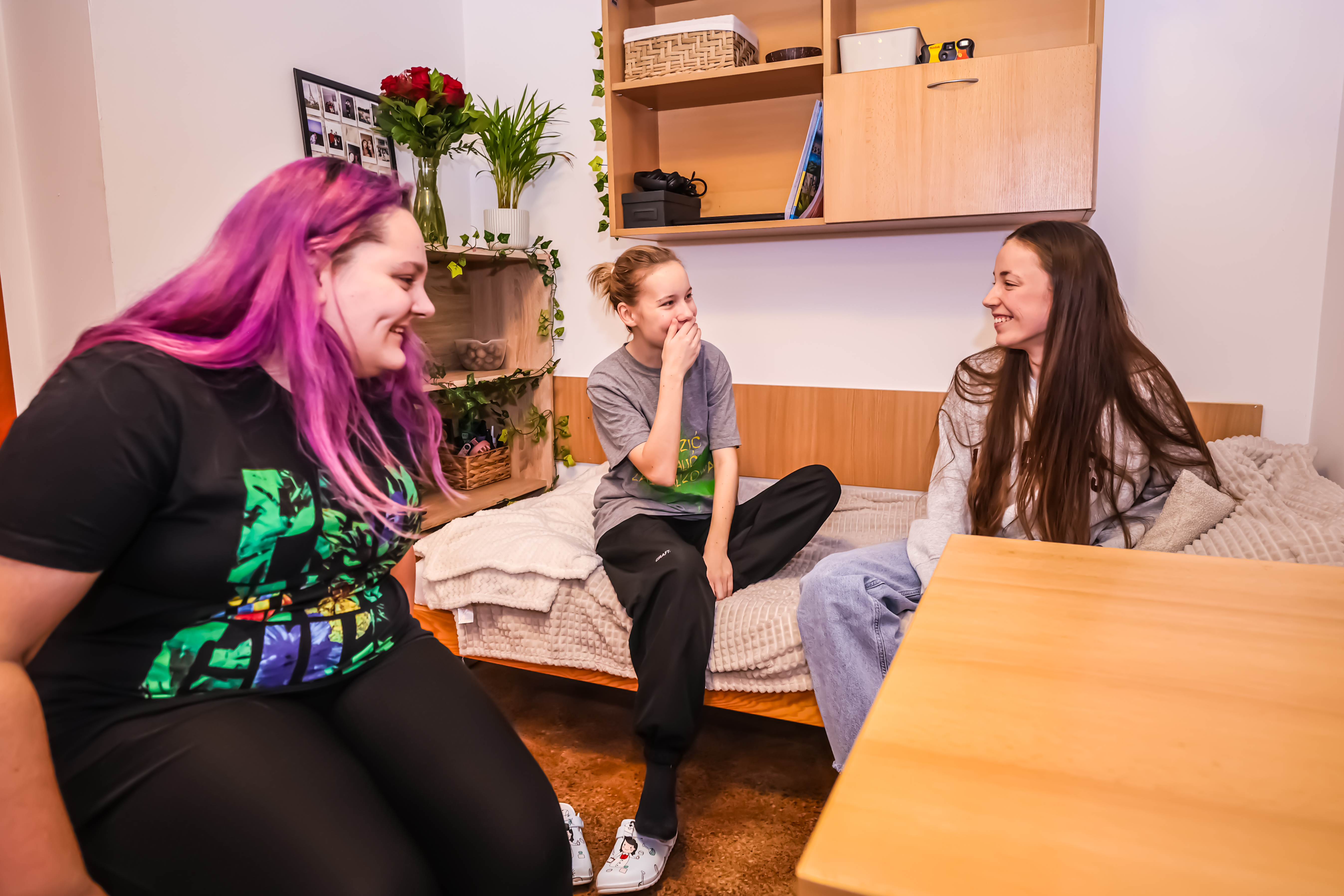 Three smiling students in the dormitory room