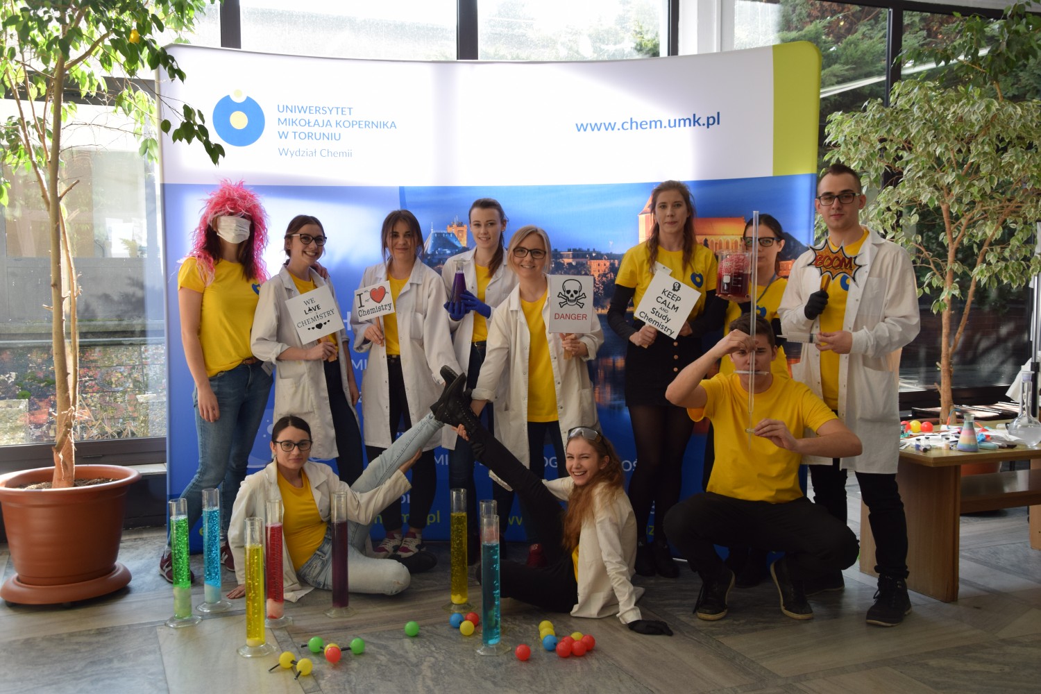 Group of students with badges in their hands in front of the faculty banner