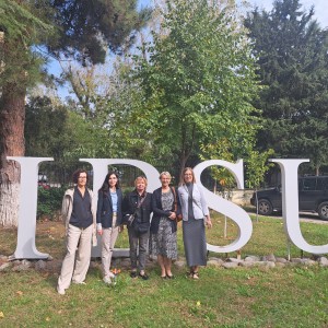 Na zdjęciu grupa wykładowców ( 5 kobiet) na tle instalacji z liter wielkości człowieka tworzących skrót nazwy Międzynarodowego uniwersytetu Morza Czarnego. Instalacja stanowi część parku należącego do uniwersytetu.. Kliknij, aby powiększyć zdjęcie.