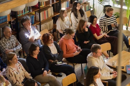 Zdjęcia sali biblioteki wydziału, na których widzimy siedzących słuchaczy i prelegentkę i jej prezentację . Kliknij, aby powiększyć zdjęcie.