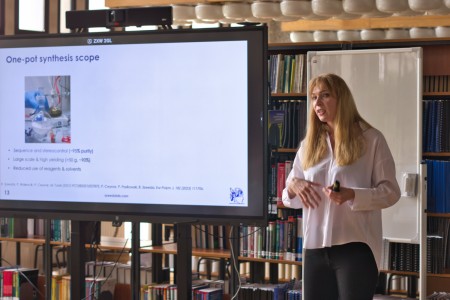Seminarium w bibliotece Wydziału Chemii. Prelegentka na tle ekranu multimedialnego referuje. Pracownicy i studenci Wydziału siedzą na przeciwko niej i słuchają interesującego wykładu.. Kliknij, aby powiększyć zdjęcie.