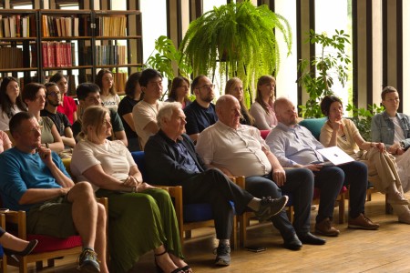 Seminarium w bibliotece Wydziału Chemii. Prelegentka na tle ekranu multimedialnego referuje. Pracownicy i studenci Wydziału siedzą na przeciwko niej i słuchają interesującego wykładu.. Kliknij, aby powiększyć zdjęcie.