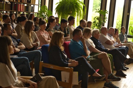 Seminarium w bibliotece Wydziału Chemii. Prelegentka na tle ekranu multimedialnego referuje. Pracownicy i studenci Wydziału siedzą na przeciwko niej i słuchają interesującego wykładu.. Kliknij, aby powiększyć zdjęcie.