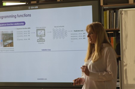 Seminarium w bibliotece Wydziału Chemii. Prelegentka na tle ekranu multimedialnego referuje. Pracownicy i studenci Wydziału siedzą na przeciwko niej i słuchają interesującego wykładu.. Kliknij, aby powiększyć zdjęcie.