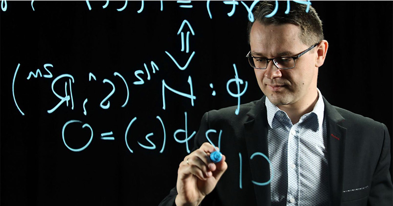 in the photo, a scientist writing mathematical formulas on the glass