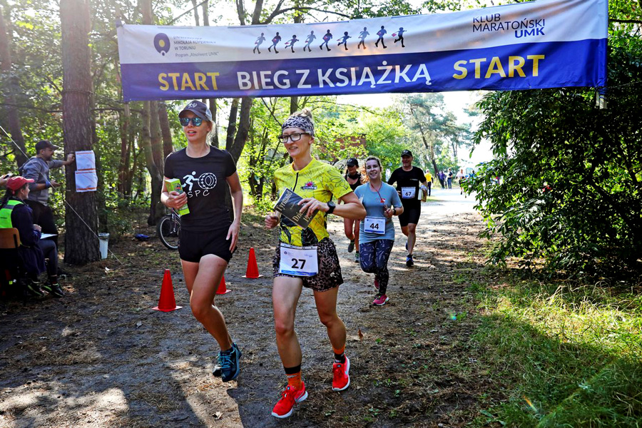 The photo shows people crossing the finish line with a book in their hand.