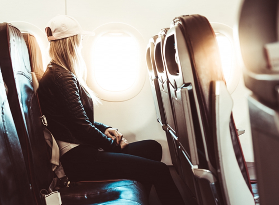 dziewczyna siedząca w samolocie i wpatrująca się w okno