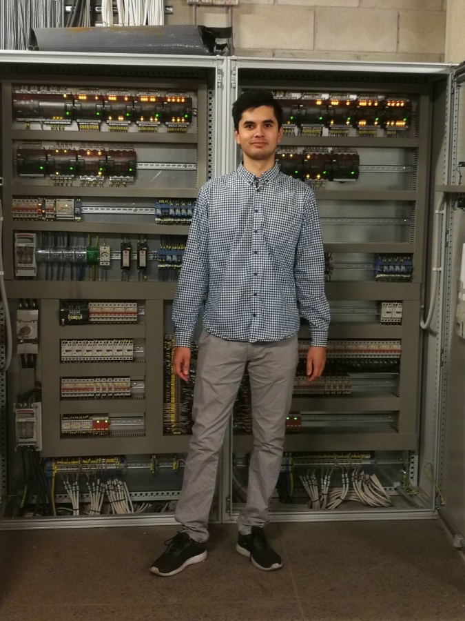 Na zdjęciu pan Bartosz Błotnicki student Automatyki i Robotyki WFAiIS na tle szafy sterowniczej