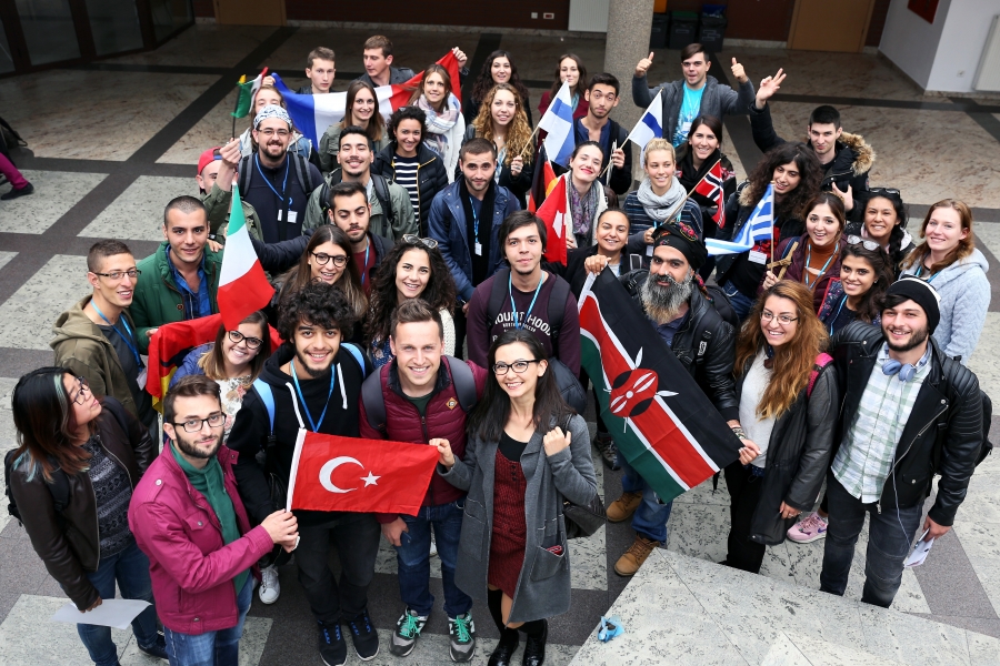 Grupa osób z zagranicy, trzymająca w dłoniach flagi swoich krajów - m.in. Turcja, Chorwacja, Szwecja. 