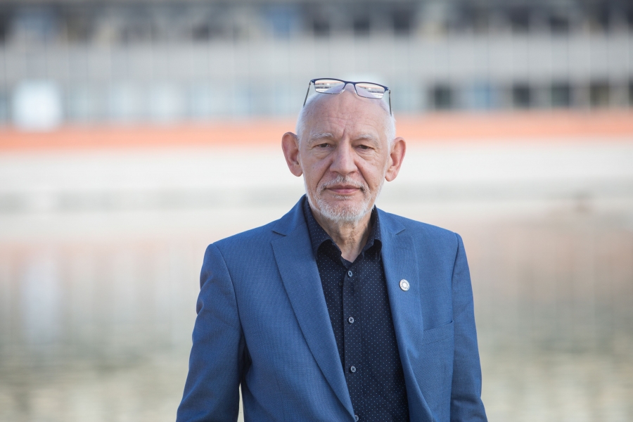 Portret JM Rektora patrzącego przed siebie (w obiektyw). Postać widoczna do pasa. Tło nieostre, 