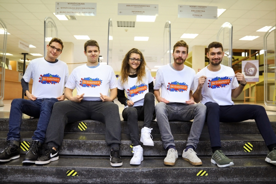 Piątka studentów wymiany Erasmus, siedząca na schodach, w promocyjnych koszulkach. 