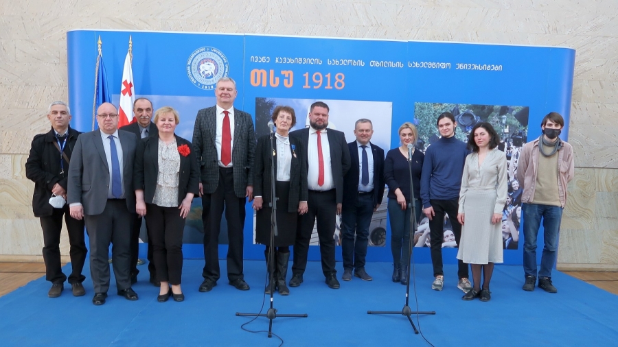 Na tle niebieskiej ścianki z nazwą konferencji ustawieni jej uczestnicy - mężczyźni i kobiety w różnym wieku