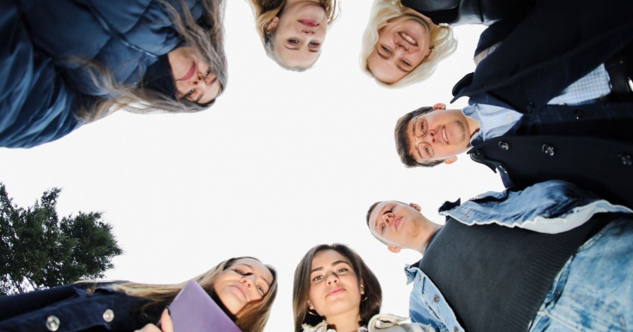 A group of students standing in circle, photo was taken from below