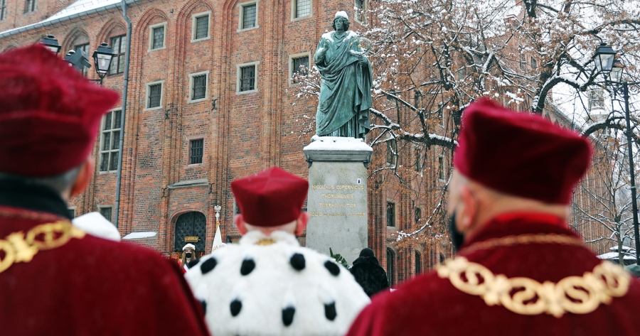 Rektorzy stojący tyłem, w tle pomnik Mikołaja Kopernika w Toruniu