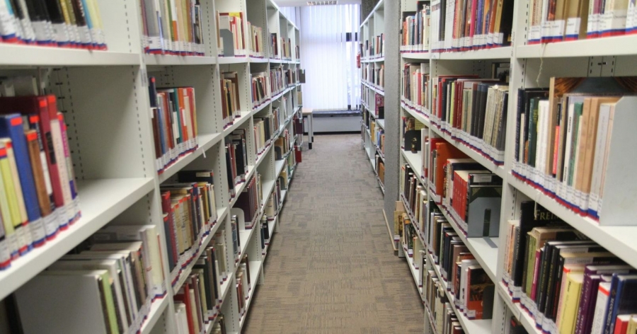 Alejka między regałami z książkami w Bibliotece Uniwersyteckiej