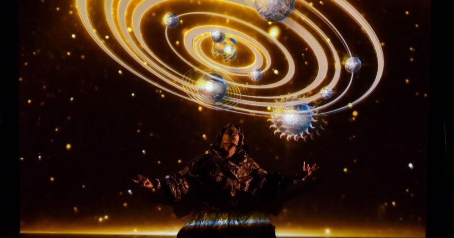 Zdjęcie postaci ucharakteryzowanej na Mikołaja Kopernika; w tle wyświetlony jest obraz przedstawiający kosmos w Ziemią w centrum naszej części wszechświata