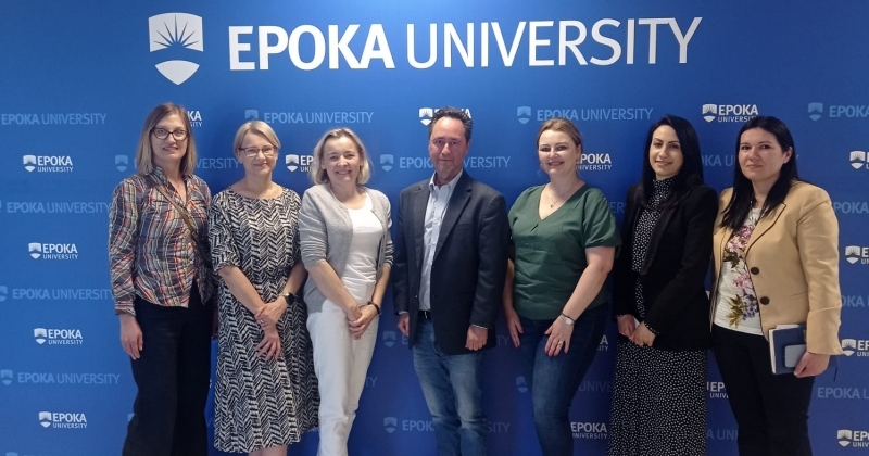 Against the background of a large banner with the name and logo of the Epoka University in Tirana, pose participants of the meeting, who are academic teachers of both universities. From the left: mgr Joanna Ososińska-Ciechomska, mgr Ewa Kowalska, mgr Hanna Łysiak, prof. dr David Felsen, mgr Katarzyna Gałka, M.A. Ada Cara, Ph.D. Alba Gerdeci.