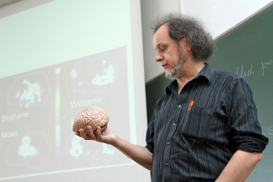 Prof. dr hab. Włodzisław Duch trzyma w lewej ręce sztuczny mózg i patrzy na niego. 